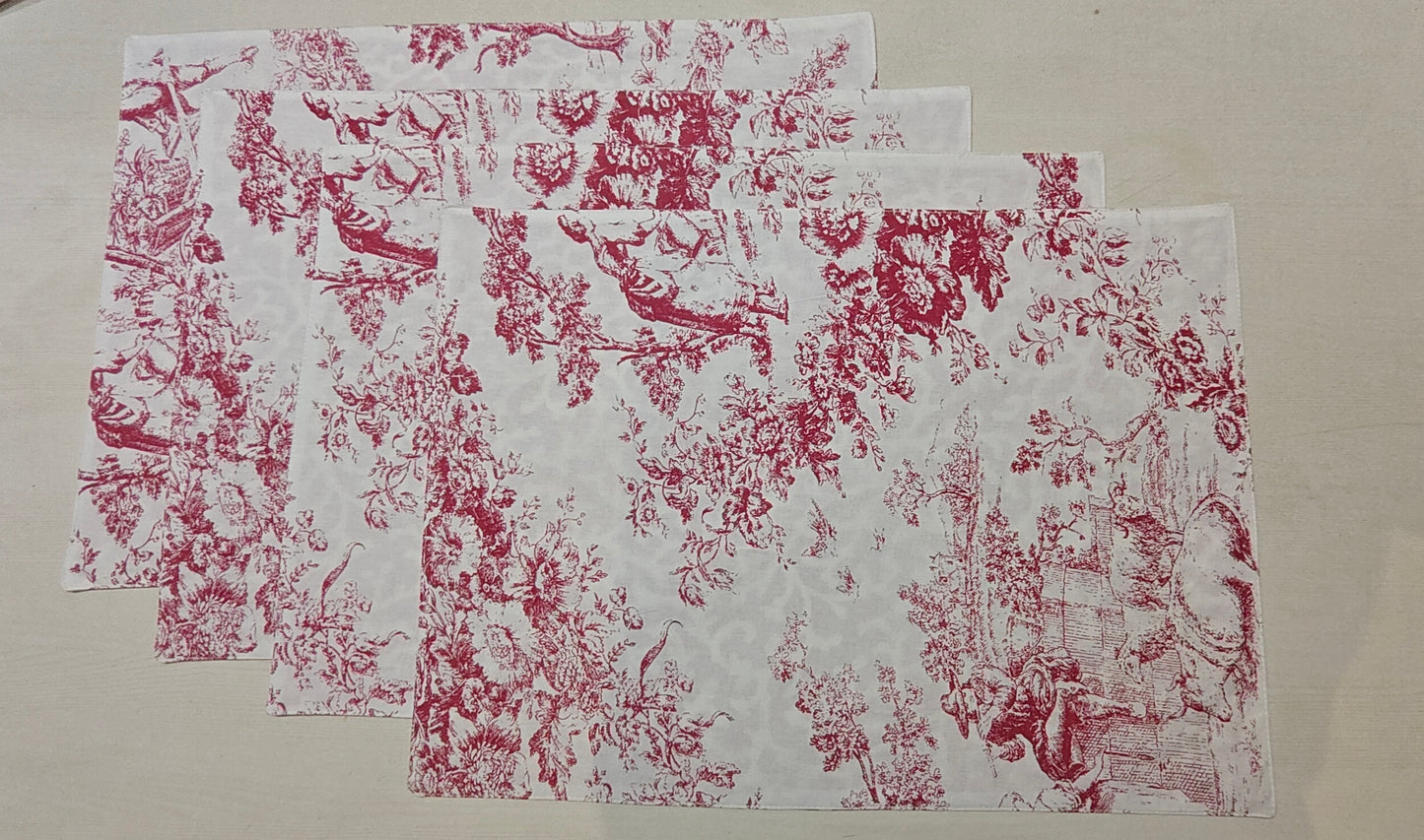 Set of red and white floral patterned placemats on a beige surface