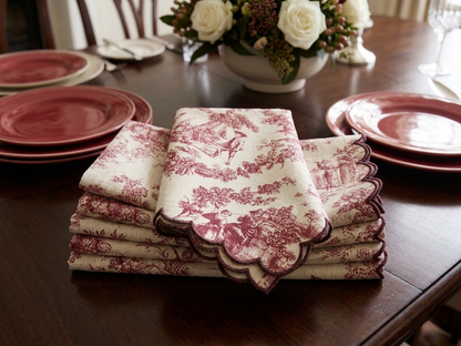Stack of red and white patterned napkins on a wooden table with floral arrangement in the background