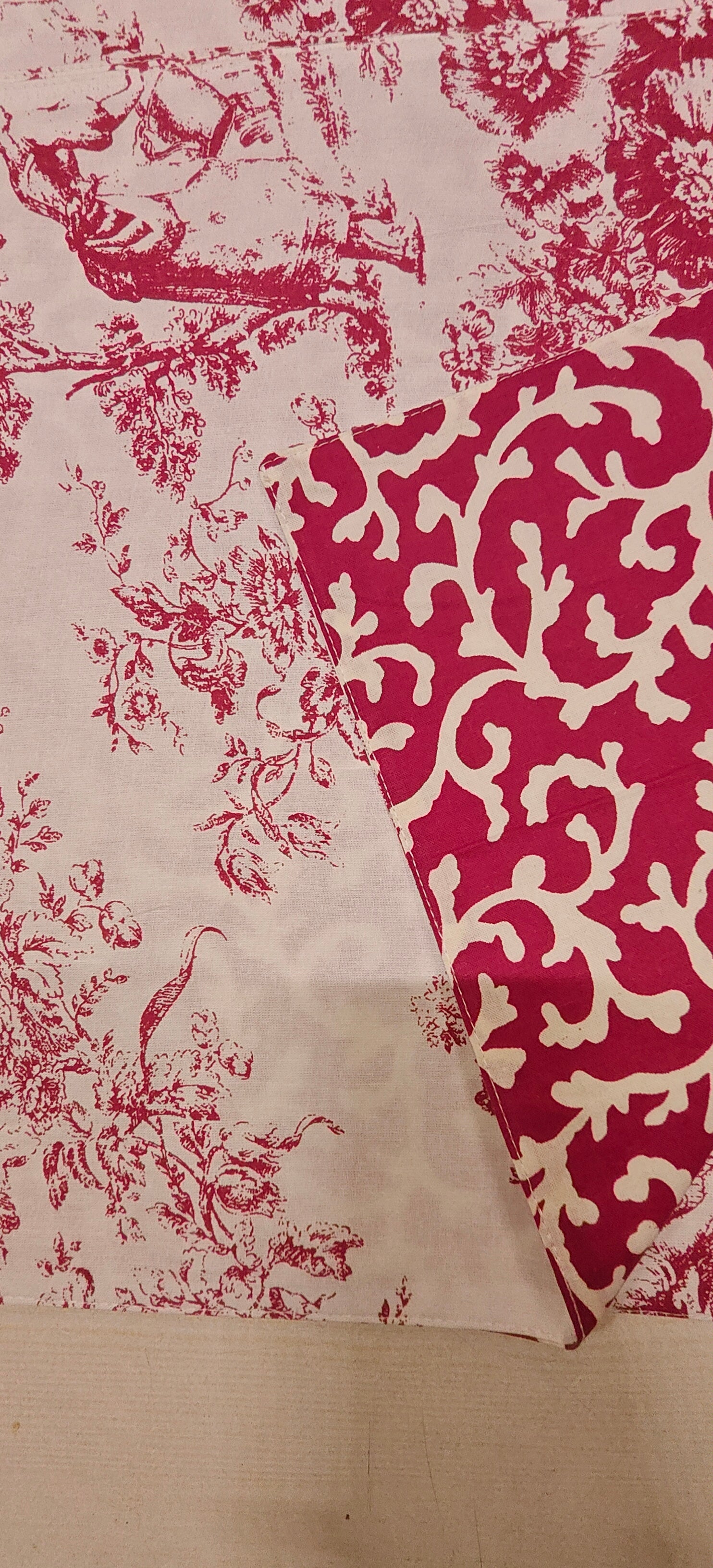 Fabric with red and white floral Placemats on a wooden surface