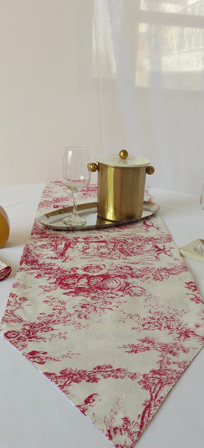 Table setting with a red and white patterned table runner, glasses, and a pot.